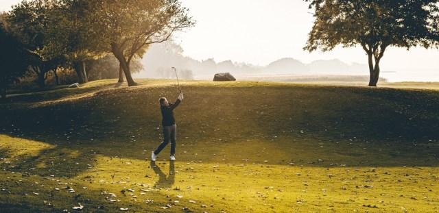 Golfer taking a swing on golf course at golden hour