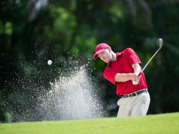 Golfer taking a swing from the bunker